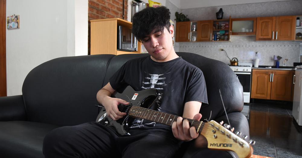 Martín Sosa tocando su guitarra en el living de su casa de Lomas